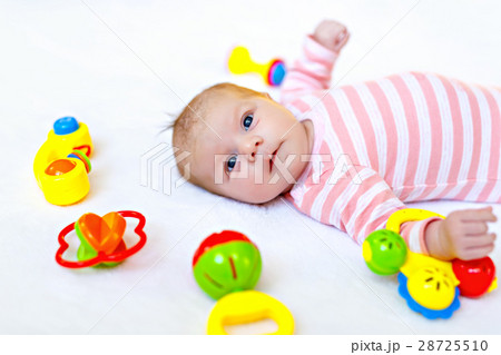 Cute baby girl playing with colorful rattle toys Cute baby girl playing with colorful rattle toys 28725510
