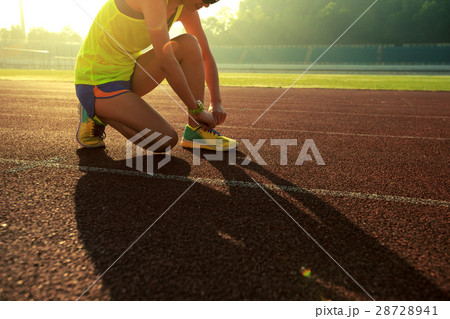 young fitness woman runner tying shoelace on track 28728941