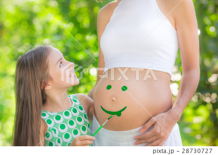 Happy child painting smile on belly of pregnant woman 28730727