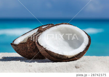 Broken brown coconut on sandy beach Broken brown coconut on sandy beach 28742375
