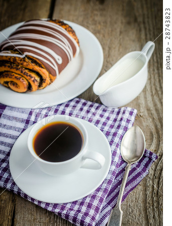 Cup of coffee and poppy bun glazed with ganache 28743823