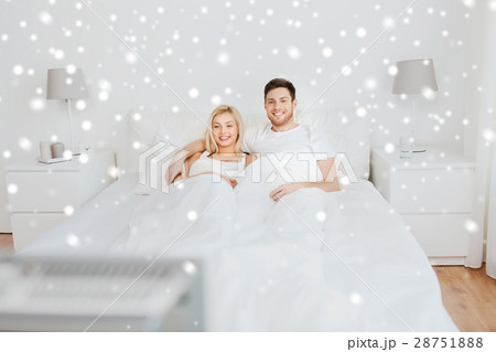 happy couple lying in bed at home and watching tv happy couple lying in bed at home and watching tv 28751888