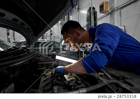mechanic man with lamp repairing car at workshop 28753318