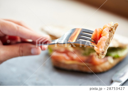 woman eating salmon panini sandwich at restaurant 28753427