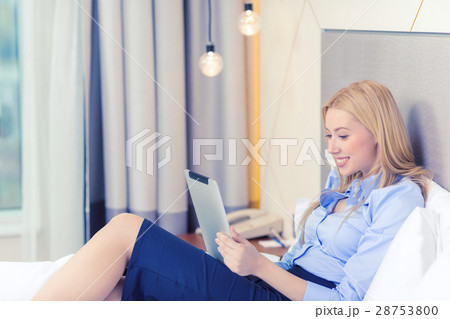 happy businesswoman with tablet pc in hotel room 28753800