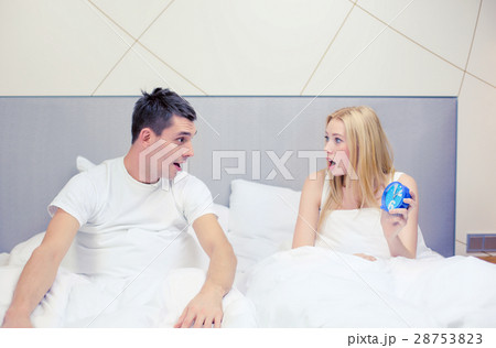 surprised couple with clock in bed 28753823