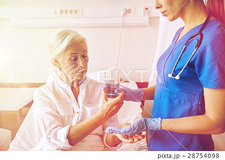 nurse giving medicine to senior woman at hospital 28754098