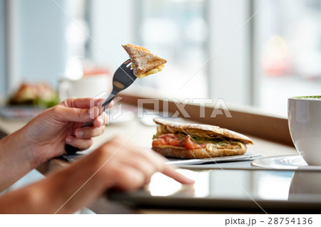 woman with tablet pc and panini sandwich at cafe 28754136