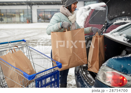 woman loading food from shopping cart to car trunk 28754700
