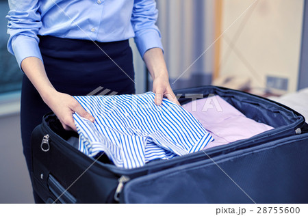 businesswoman packing clothes into travel bag businesswoman packing clothes into travel bag 28755600