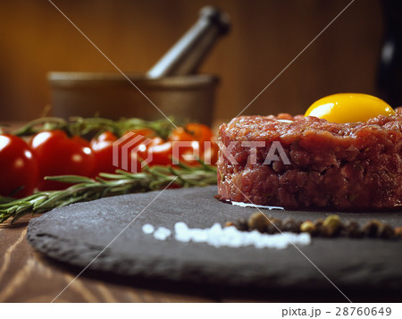 Beef tartar with an egg on a stone plate. 28760649