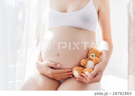 Pregnant woman with knitted toy teddy bear. 28762863