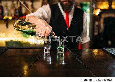 Barkeeper pouring alcoholic beverage in glass Barkeeper pouring alcoholic beverage in glass 28776408
