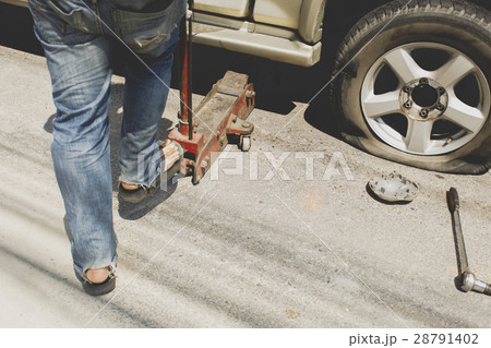 A man changing the wheel at the side of the road 28791402