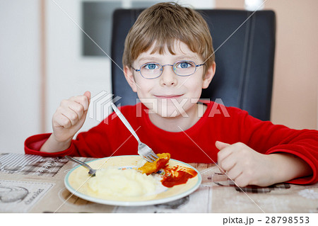 Adorable little school boy eating potato mash and Adorable little school boy eating potato mash and 28798553