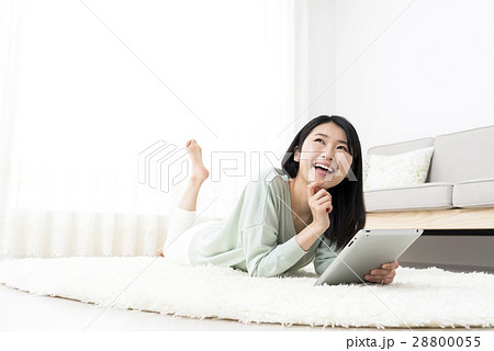 ラグにうつ伏せで寝転がってタブレットを操作する若い女性 ラグにうつ伏せで寝転がってタブレットを操作する若い女性 28800055