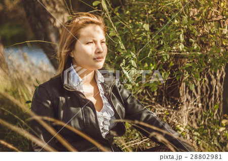 Asian sits alongside a tree Asian sits alongside a tree 28802981