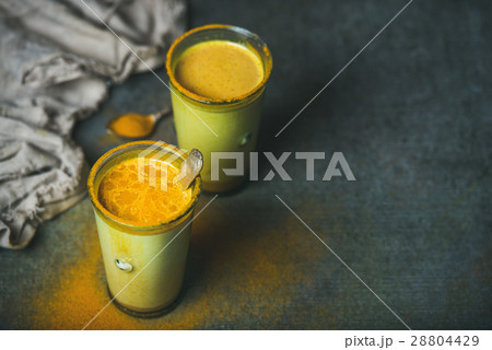 Golden milk with turmeric powder in glasses over 28804429