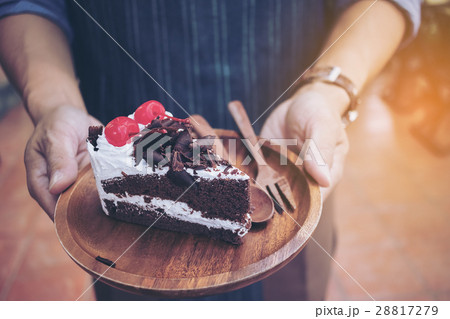 Male waiter holding plate with cake in cafe 28817279