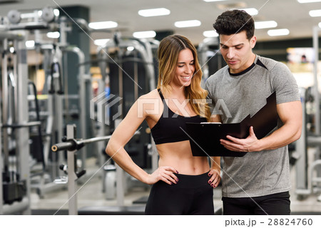 Personal trainer and client looking at her progress at the gym 28824760
