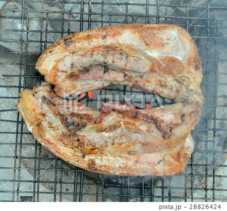 Grilled pork  over flames on the grill. 28826424