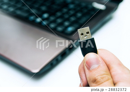 Man holding USB plug. Laptop in background 28832372