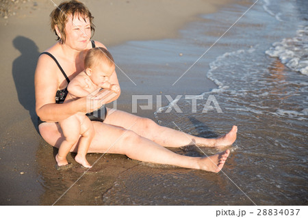 Naked baby on aged woman hands at beach 28834037