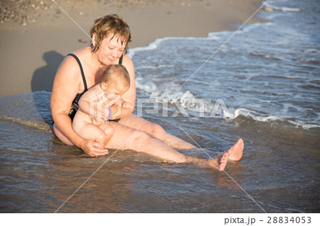 Naked baby on aged woman hands at beach 28834053