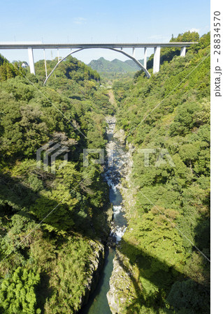 新緑の高千穂峡と国道218号線高千穂バイパス道路に架かる多角形アーチ形の神都高千穂大橋と祖母山連山 28834570