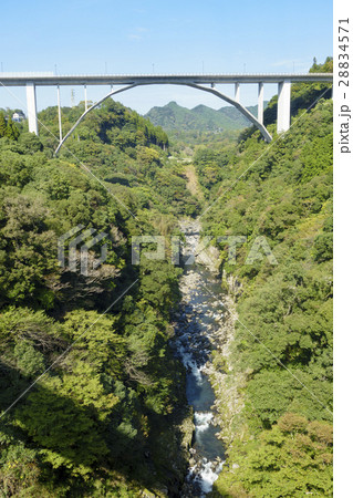 新緑の高千穂峡と国道218号線高千穂バイパス道路に架かる多角形アーチ形の神都高千穂大橋と祖母山連山 28834571