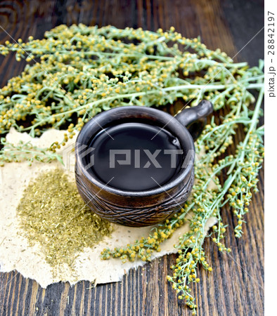 Tea with wormwood in cup on dark board 28842197