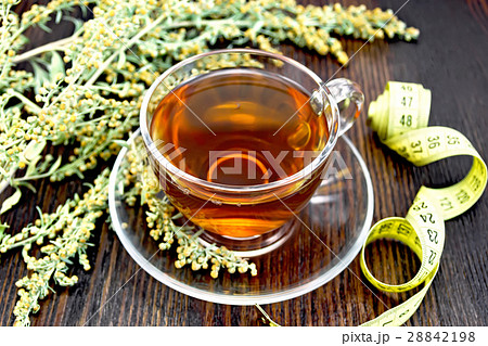 Tea with wormwood in glass cup and meter on board 28842198