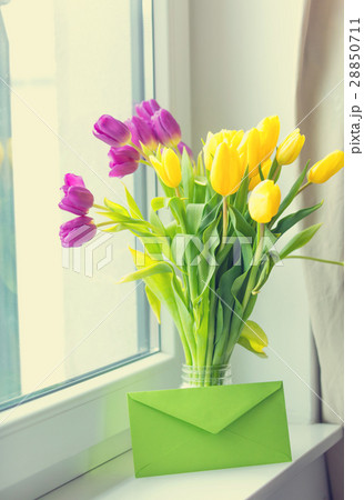bunch of tulips and envelope on windowsill 28850711