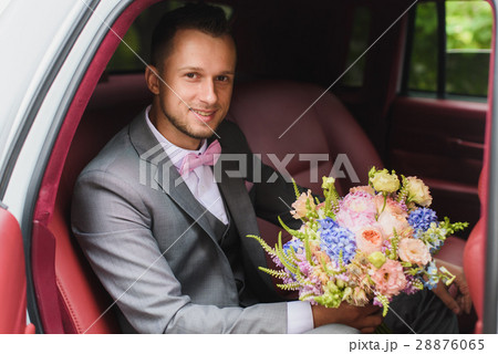 Groom with bouquet in the wedding car 28876065