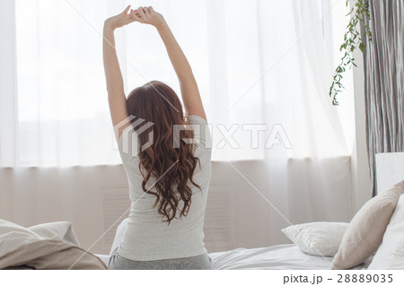 Female stretching sitting on bed in morning Female stretching sitting on bed in morning 28889035