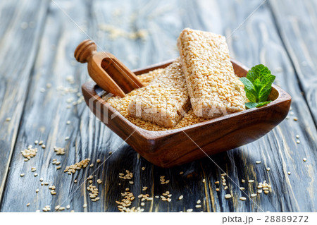 Bowl with sesame bars and a wooden scoop. Bowl with sesame bars and a wooden scoop. 28889272