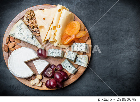 assorted cheeses, nuts and grapes on a black 28890648