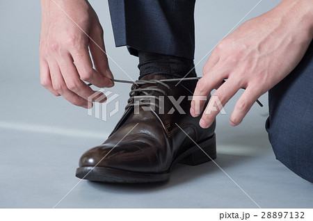 靴紐を結ぶ男性足元の写真素材