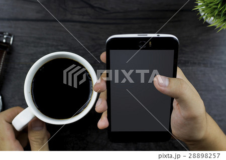 Using smartphone and holding a coffee cup 28898257