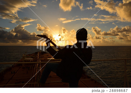 A man playing guitar and singing at sunset on boar A man playing guitar and singing at sunset on boar 28898687