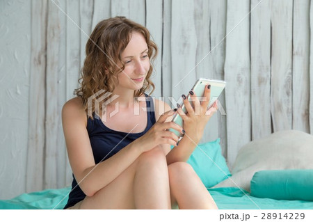 Young curly woman lying in the bed with tablet pc. Young curly woman lying in the bed with tablet pc. 28914229