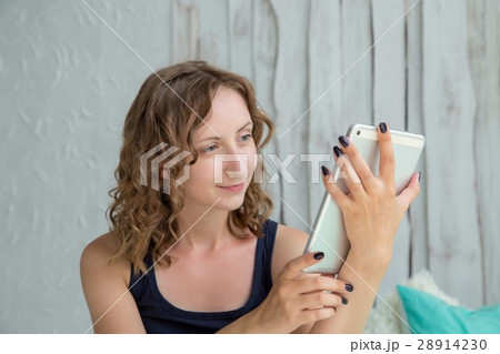 Young curly woman lying in the bed with tablet pc. Young curly woman lying in the bed with tablet pc. 28914230
