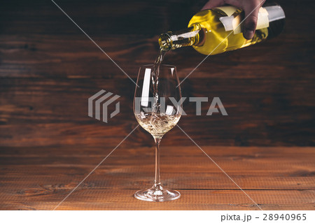 Pouring white wine from a bottle in a close up  28940965