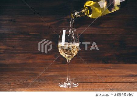 Pouring white wine from a bottle in a close up 28940966