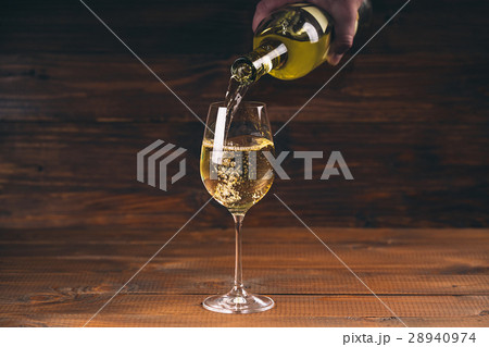 Pouring white wine from a bottle in a close up  28940974