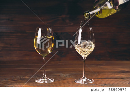 Two glasses pouring white wine from a bottle  28940975