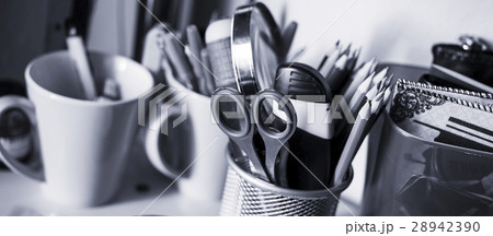 Writing instruments in glasses on a shelf. Writing instruments in glasses on a shelf. 28942390
