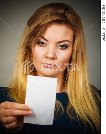 Seriously worried woman looking at piece of paper Seriously worried woman looking at piece of paper 28943668