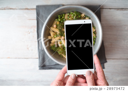 A woman is photographing a cooked salad closeup 28973472