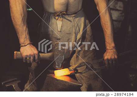 Blacksmith working metal with hammer on the anvil Blacksmith working metal with hammer on the anvil 28974194